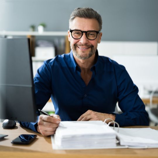 A billing specialist smiling while sitting at his desk