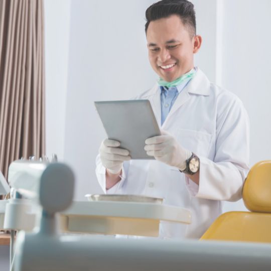 A dentist smiling while checking his tablet