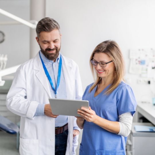 A dentist and assistant looking at a tablet together