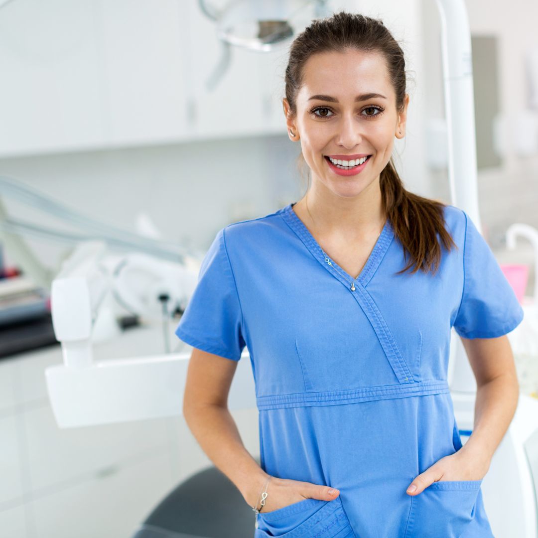 a smiling dental technician dressed in srubs