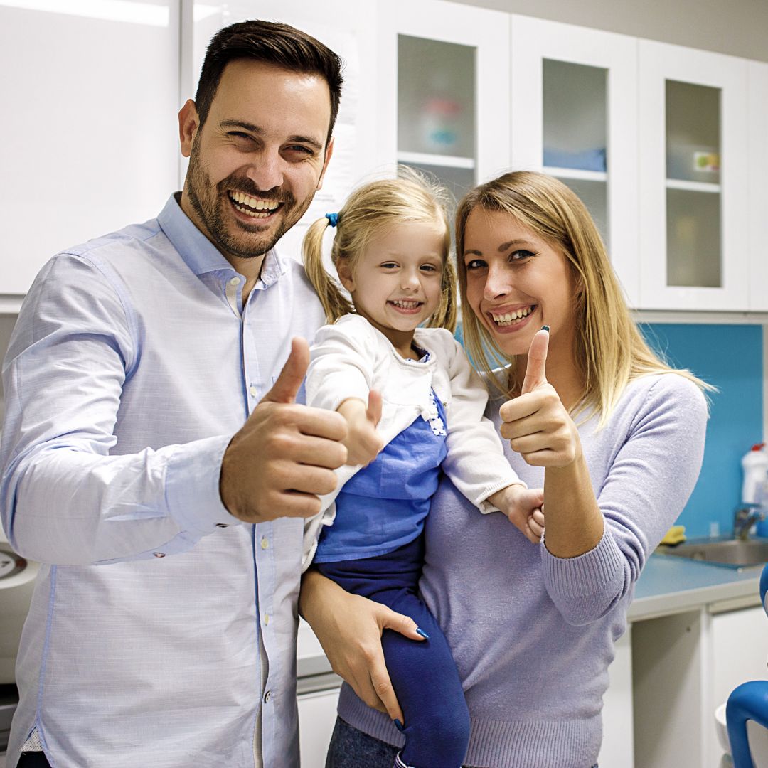 dentist smiling with patient and her parent